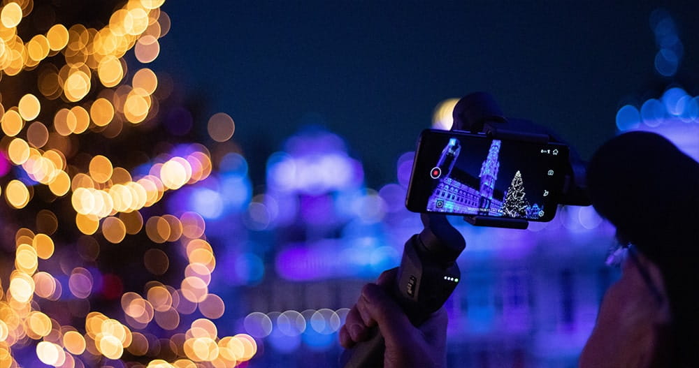 Photographer taking picture of Christmas tree in festive photograph using smart phone